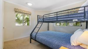 a bedroom with a bunk bed and two windows at Pacific Waves Apartments in Noosa Heads +2 photos