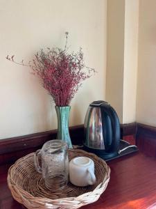 a table with a wicker basket with a vase and a tea kettle at Nam Ou Breeze in Ban Ngoy-Nua