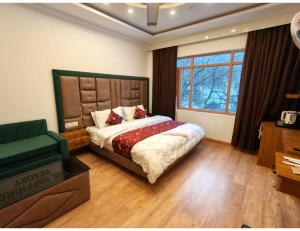 a bedroom with a bed and a couch and a window at Velour Pines Pahalgam in Pahalgām