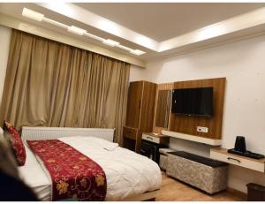 a bedroom with a bed and a flat screen tv at Velour Pines Pahalgam in Pahalgām