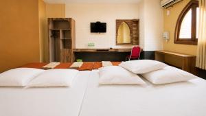 two beds with white pillows in a hotel room at Ventions Sharia Hotel in Jomblang