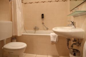 a bathroom with a sink and a toilet and a tub at TOP Hotel Amberger in Würzburg