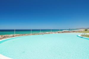a swimming pool with the ocean in the background at Bellevue Sardinia Resort, Affiliated by Meliá in Valledoria