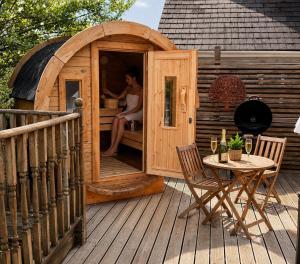 a woman is sitting in a wooden house on a deck at 1 Romantic cabin for two with outdoor bath and Sauna! in Pont Sticill