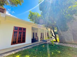 a white house with a tree in the yard at Blue Heaven Guest House Wellawaya in Wellawaya