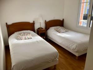 two beds in a small room with a window at Villa Médicis Trouville-sur-mer in Trouville-sur-Mer