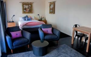 a bedroom with a bed and two chairs and a table at New Norfolk Holiday Apartments in New Norfolk