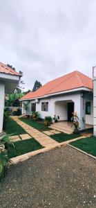 a white house with a red roof and a yard at chama haven apartments in Nkoanrua
