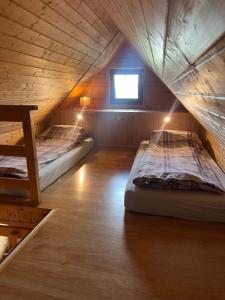 two beds in a wooden cabin with a window at Domki Piękny Widok u Karola in Solina