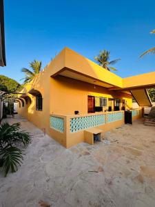 a yellow building with a bench in front of it at The Mason Hideout in Watamu