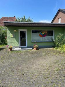 a green house with flowers in front of it at Kleines grünes Gästehaus in Altenbeken