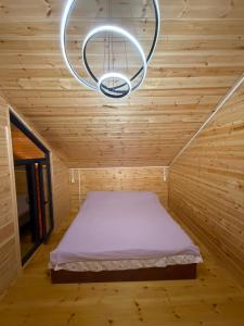 a bed in a wooden room with a chandelier at Adam in Chon-Sary-Oy