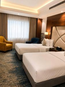 a hotel room with two beds and a chair at IQ Hotel alhamra فندق اي كيو الحمراء in Jeddah +18 photos
