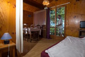 a man standing in a room with a bed and a table at chalets studio du vieux frêne in Saint-Hilaire