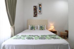 a bedroom with a bed with white sheets and a window at Bisma Balcony Homestay in Yogyakarta