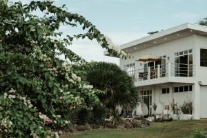 a white house with a balcony and flowers at Balay Kalachuchi in Barili