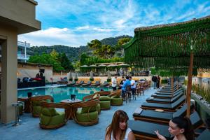 a pool with tables and chairs and people sitting around it at Hotel Pavlou in Poros