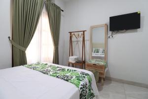 a bedroom with a bed and a tv and a mirror at Bisma Balcony Homestay in Yogyakarta