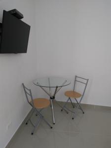 mesa de cristal con 2 sillas y TV en Hotel Boutique Santorini Class, en Sincelejo