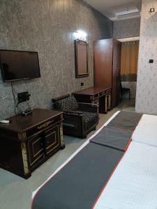 a room with a bed and a desk and a tv at Hotel Rahul Palace in Nagpur