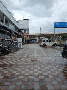 a parking lot with a white car parked in front of buildings at Hotel Rahul Palace in Nagpur