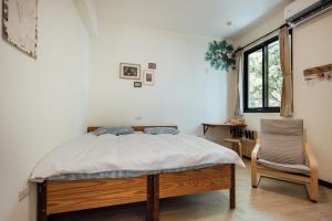 a bedroom with a bed and a chair and a window at Tree House Café & Homestay in Tongluo