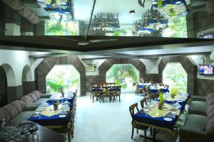 a dining room with blue tables and chairs and windows at Kingdom Hotel in Moga