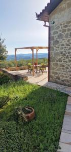 a patio with a table and benches in the grass at Olive Stonehouse Sea and Mountain View in Áyios Míron +7 photos
