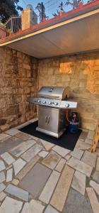 a grill in a patio with a stone wall at Olive Stonehouse Sea and Mountain View in Áyios Míron