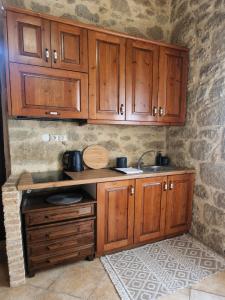 a kitchen with wooden cabinets and a sink at Olive Stonehouse Sea and Mountain View in Áyios Míron
