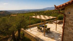 a patio with a table and chairs under a roof at Olive Stonehouse Sea and Mountain View in Áyios Míron