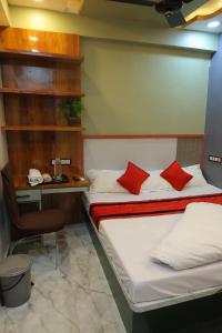 a bedroom with a bed with red pillows and a desk at Hotel SR Imperial in Kolkata +11 photos