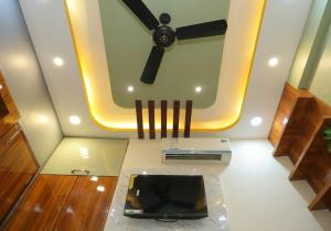 a living room with a ceiling fan and a television at Hotel SR Imperial in Kolkata