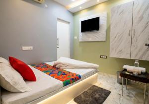 a small bedroom with a bed and a tv on the wall at Hotel SR Imperial in Kolkata