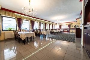 a dining room with tables and chairs and chandeliers at Hotel Ferum in Šaca