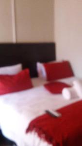a close up of a bed with red pillows at Valley Guest House in Pretoria