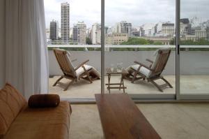 ein Wohnzimmer mit 2 Stühlen und einem Tisch auf dem Balkon in der Unterkunft Design cE - Hotel Boutique de Diseño in Buenos Aires