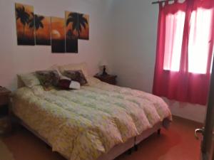a bedroom with a bed and two windows with red curtains at Villa El Refugio in Potrerillos