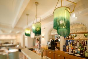 a bar with green chandeliers hanging over a counter at Chez Gratien Hôtel Bistro Spa in Villeneuve-dʼAveyron