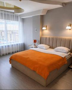 a bedroom with a large bed with an orange blanket at Seven Eleven Apartment HOTEL in Most City in Dnipro