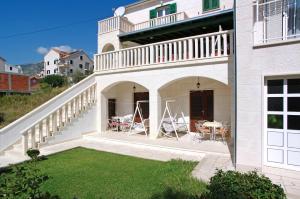 a white house with a balcony and a yard at Apartments Villa Adria Bol in Bol