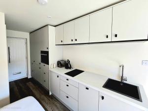 a kitchen with white cabinets and a sink at Studio 3 - Stylish apartment central to hospital and racecourse in Cheltenham