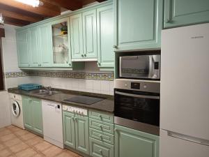 a kitchen with green cabinets and a stove top oven at La casuca in Noja