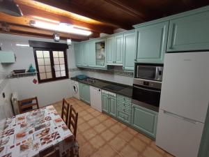 a kitchen with green cabinets and a table with a white refrigerator at La casuca in Noja +11 photos