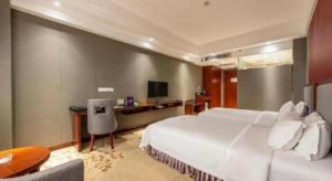 a bedroom with a large white bed and a desk at Shunde Emperor Hotel in Shunde