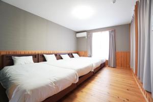 two beds in a room with a large window at 白浜みんと in Shirahama