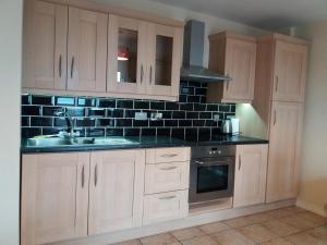 a kitchen with white cabinets and a black tiled wall at Atlantic View in Bundoran