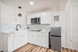a white kitchen with a sink and a refrigerator at Clair de Lune Studio A Charming Kokomo Stay in Kokomo