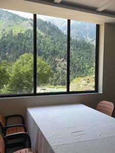 a room with a table and chairs and a large window at Kove Hotel & Resort in Naran