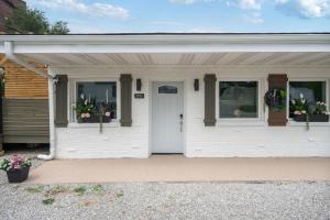 a white house with two windows and a door at Clair de Lune Studio A Charming Kokomo Stay in Kokomo